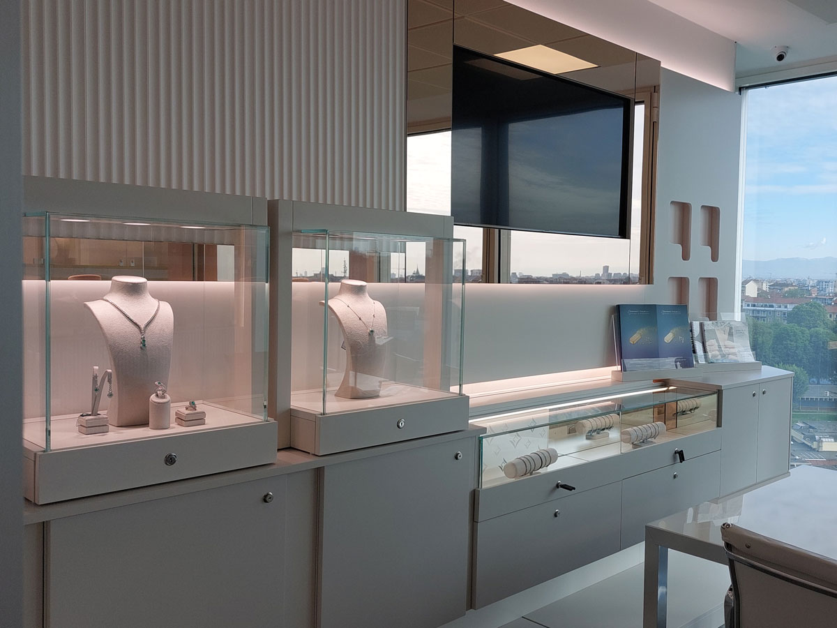 Le vetrine dello showroom Conte Diamonds di Milano: collane e anelli esposti su busti in tessuto chiaro, con le finestre che si aprono sulla città